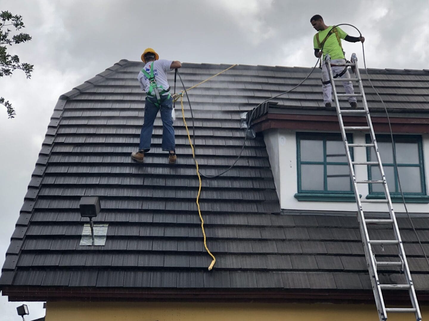 Two workers installing or repairing a roof on a cloudy day.